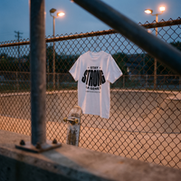 T-shirt Gen Z blanc « Stay Strong la Gène Z » accroché au grillage d'un skatepark au crépuscule – tshirt genz pas cher CHT'M