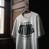 T-shirt Gen Z gris avoine « Stay Strong la Gène Z » sur cintre en bois dans un intérieur sombre – t-shirt manif original CHT'M