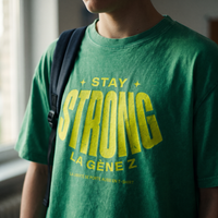Gros plan du print jaune fluo « Stay Strong la Gène Z » sur le t-shirt oversized délavé vert prairie porté – CHT'M Boutique