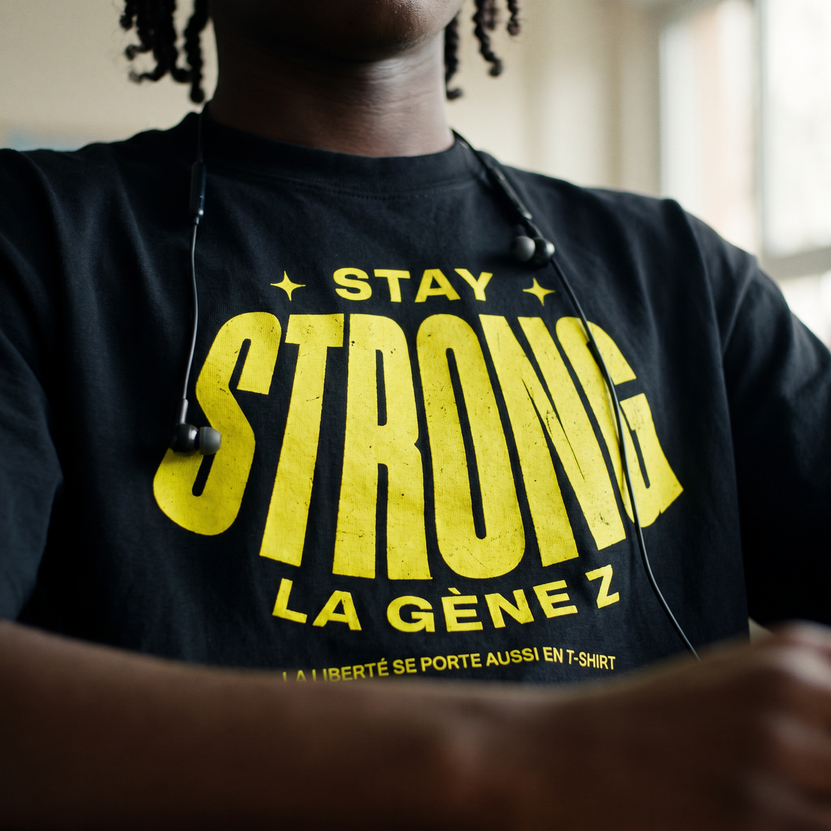 Gros plan du print jaune fluo « Stay Strong la Gène Z » sur le t-shirt oversized noir porté – CHT'M Boutique