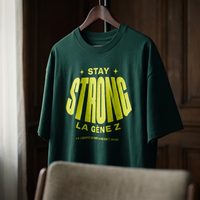 Gros plan du t-shirt oversized Gen Z vert bouteille « Stay Strong la Gène Z » sur cintre – CHT'M Boutique