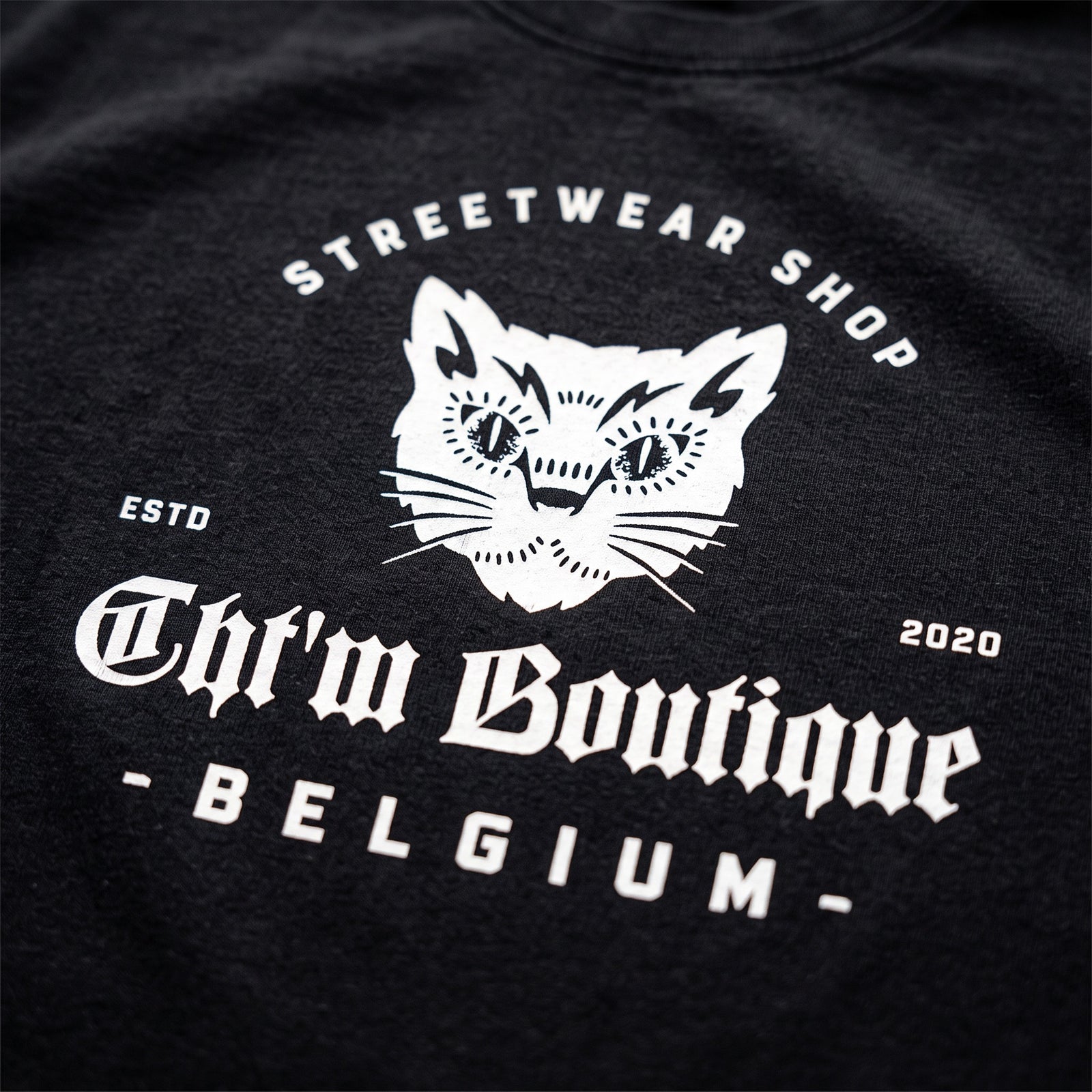 Gros plan du logo chat CHT'M Boutique Belgium imprimé sur le t-shirt oversized noir