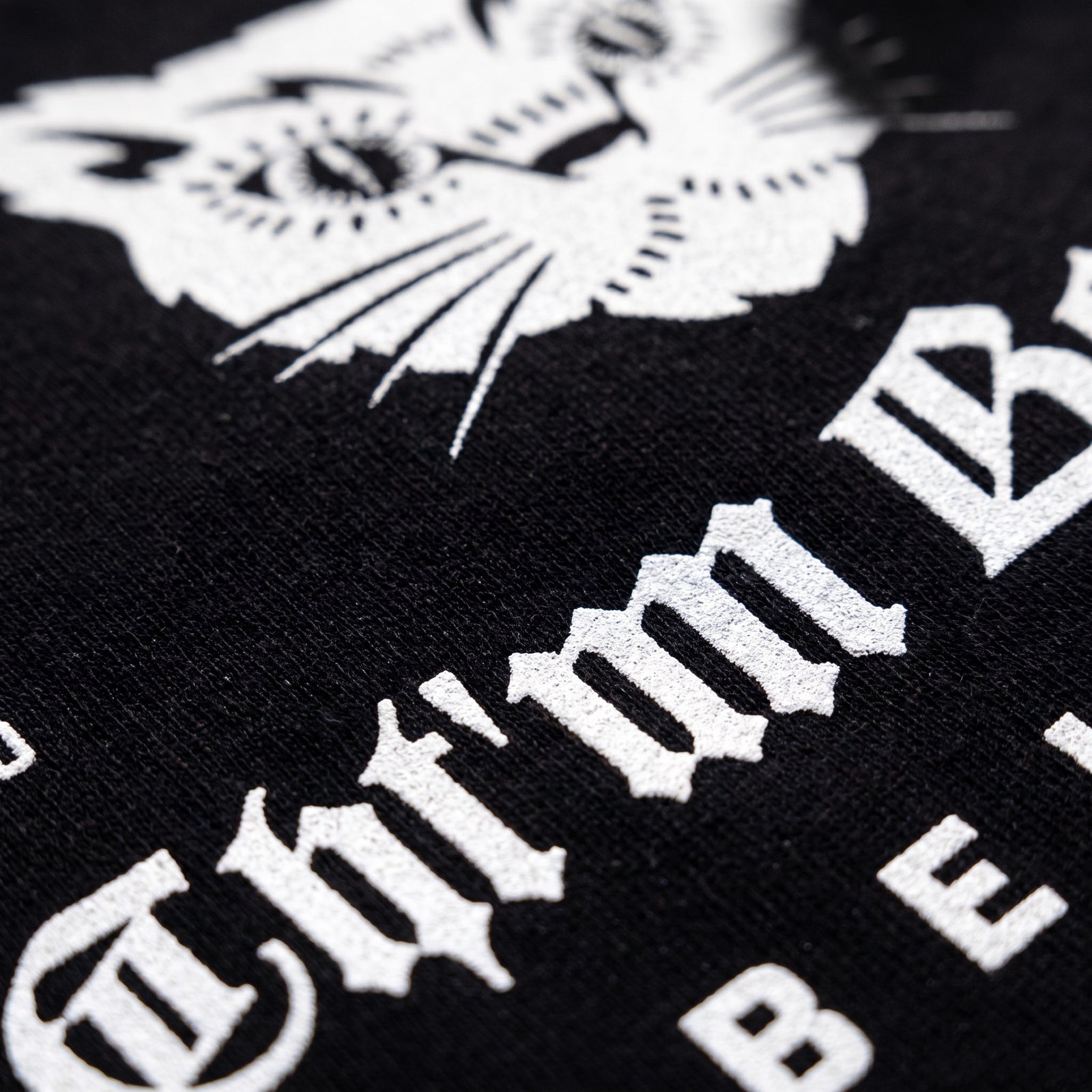 Macro de l'impression blanche du logo chat sur le coton noir du t-shirt oversized CHT'M