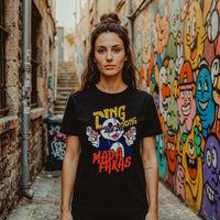 Femme portant le t-shirt panda original noir Ding Dong Mada Fakas devant un mur de street art