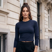 Femme portant le t-shirt manches longues original femme raglan slim bleu marine, ambiance urbaine au crépuscule