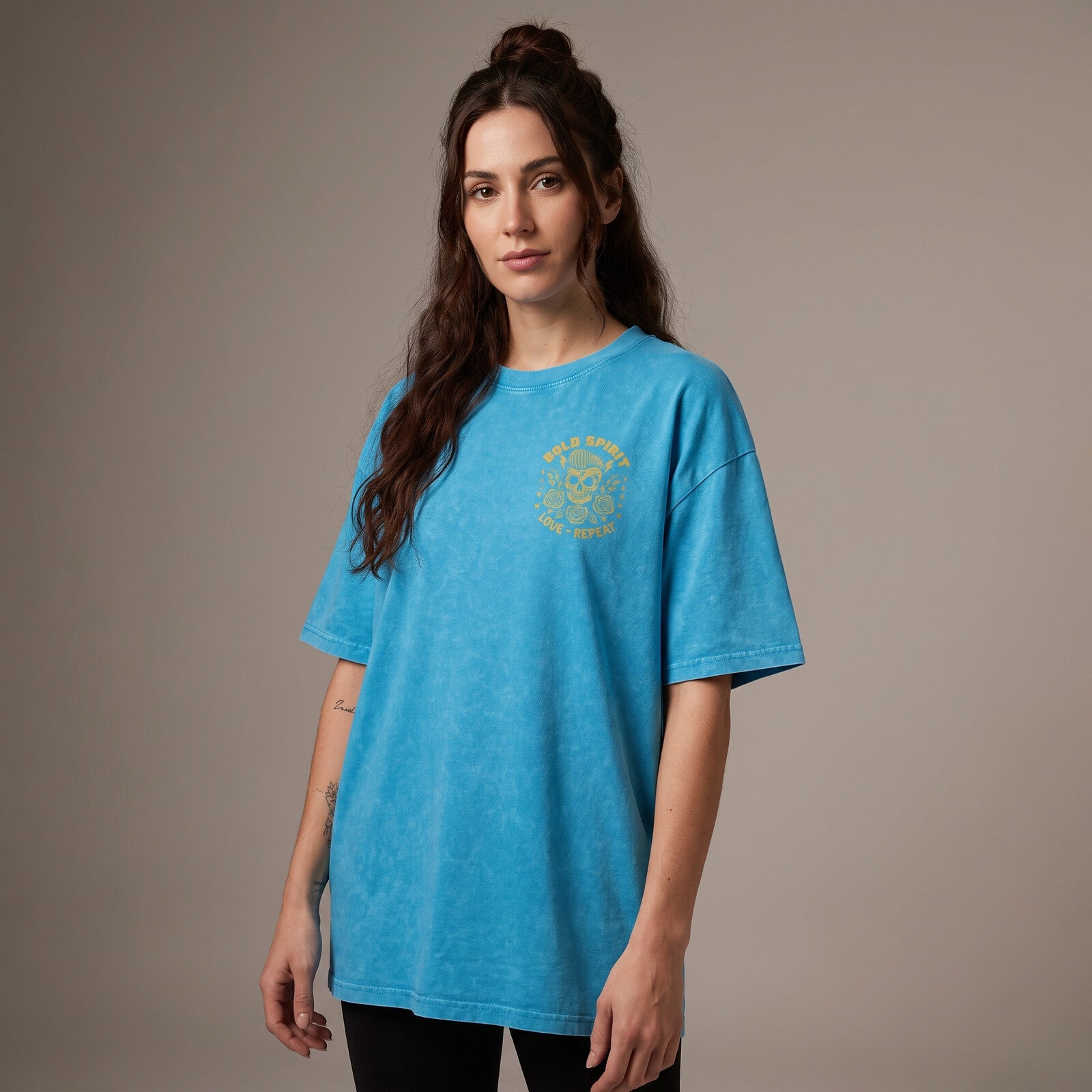 Femme portant le t-shirt tête de mort bleu lagon oversize vu de face, badge Bold Spirit sur la poitrine