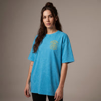 Femme portant le t-shirt tête de mort bleu lagon oversize vu de face, badge Bold Spirit sur la poitrine