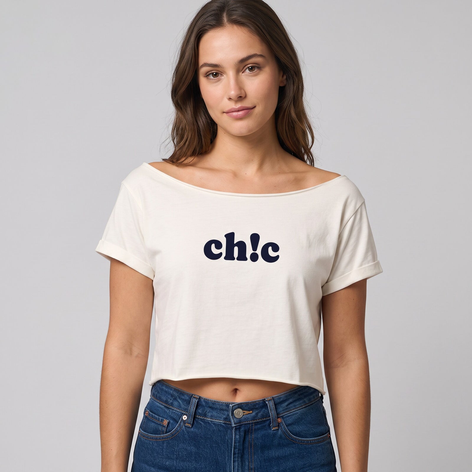 Crop top ecru a col bateau et manches roulees, imprime ch!c, porte avec un jean brut sur fond de studio gris