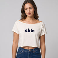 Crop top ecru a col bateau et manches roulees, imprime ch!c, porte avec un jean brut sur fond de studio gris
