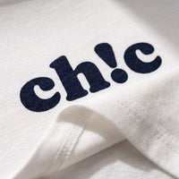 Gros plan sur le lettrage ch!c bleu marine floque et sur l'ourlet roule d'un crop top femme en coton blanc