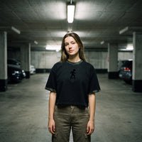 Crop top skate noir délavé et col camouflage, porté avec un cargo kaki entre les voitures d'un parking
