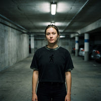 Crop top oversized noir délavé à bords camouflage, pictogramme skateur, porté dans un parking souterrain