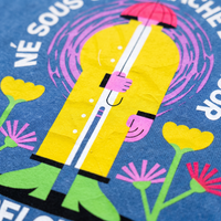 Macro du design : bonhomme en ciré jaune, parapluie rose et fleurs sérigraphiés sur le coton bleu