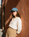 Casquette en jean bleue brodée fleur peace portée devant un mur terracotta au soleil