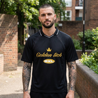 Homme en maillot de foot Golden Tich noir en rue – look streetwear, design doré Golden Tich et badge BXL