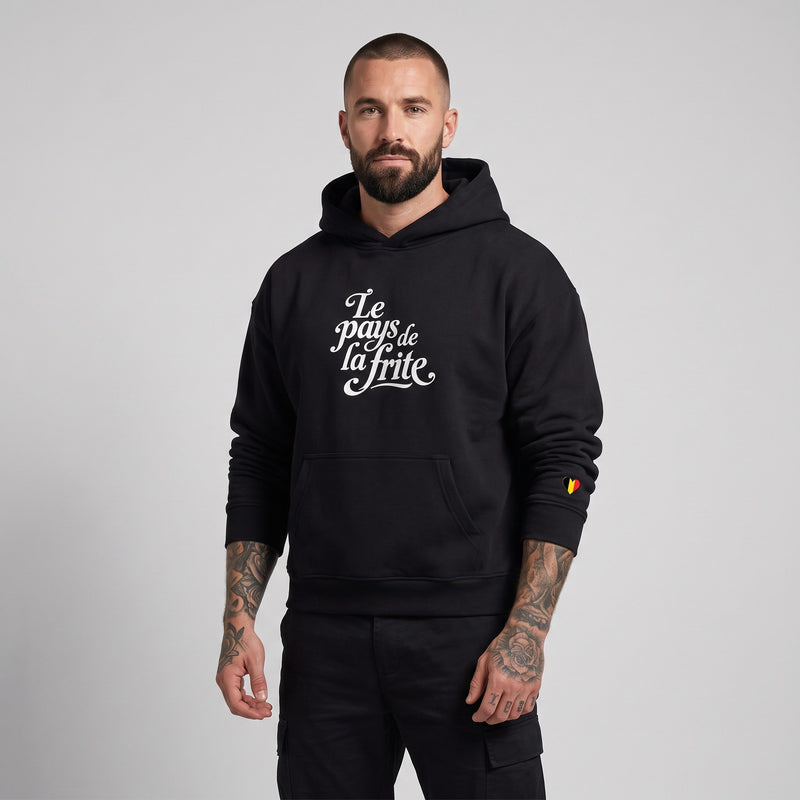 Homme portant le hoodie belge original Le Pays de la Frite noir oversize, print blanc, studio