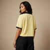 Vue de dos du maillot foot belge femme original – crop top oversized jaune, col noir et bords de manches noirs