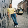 Maillot foot belge femme original en look streetwear dans une rue de Bruxelles avec tram et jean baggy