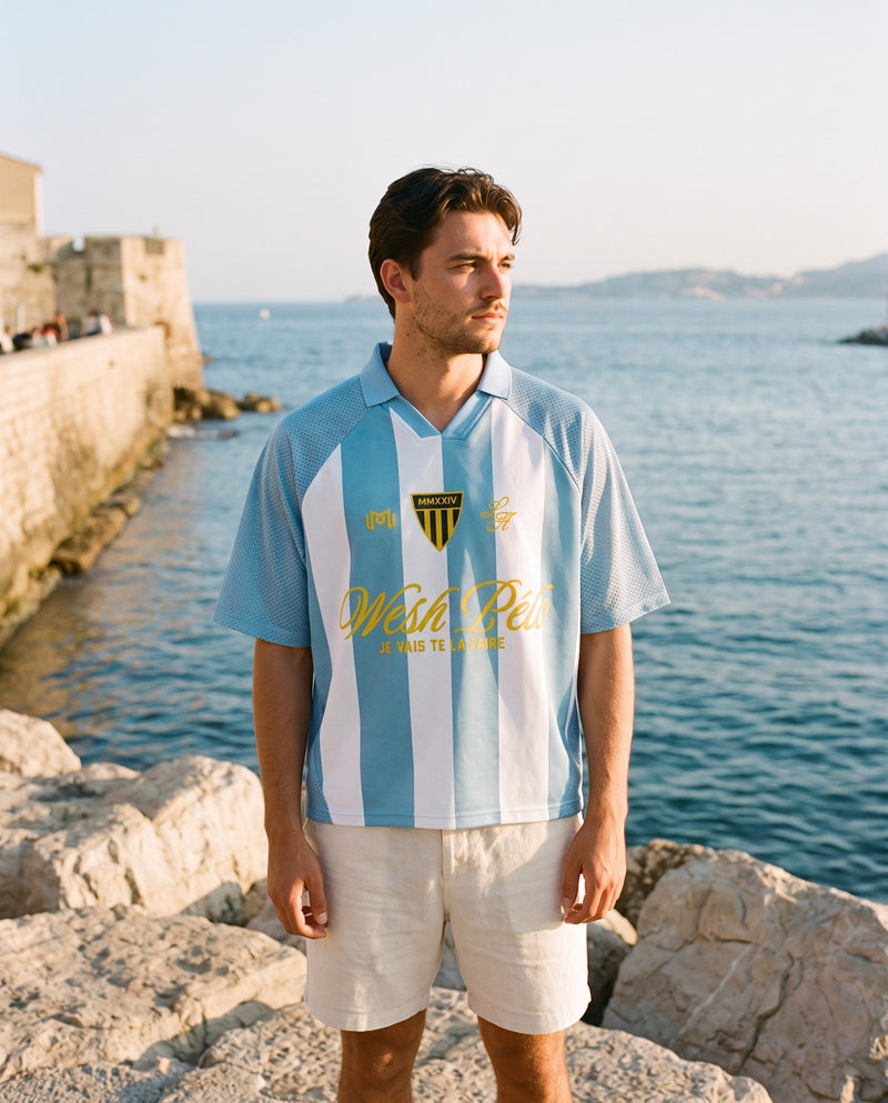 Homme portant le maillot de foot Wesh Pélo Bleu Ciel & Blanc au bord de mer méditerranéen