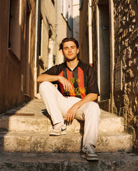 Homme assis portant le maillot de foot oversize Wesh Pélo Noir & Rouge en streetwear méditerranéen