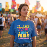 Femme en t-shirt bleu au lettrage multicolore Allez tous vous faire en couleurs, dans un festival aux drapeaux colorés