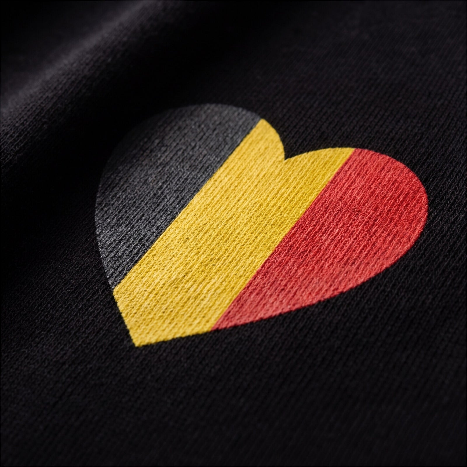 Gros plan sur le coeur noir jaune rouge imprime sur le coton lourd noir d'un t-shirt belge