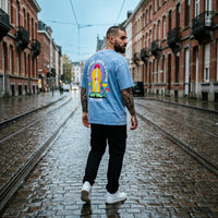 Homme de dos dans une rue pavée belge portant le t-shirt drache d'amour, imprimé dos bien visible