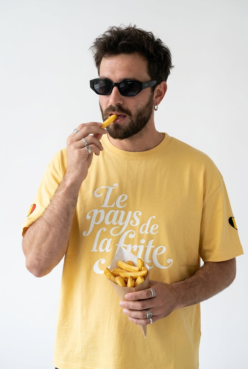T-shirt belge oversized jaune Le Pays de la Frite porté avec un cône de frites