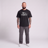 Homme barbu tatoué portant le t-shirt belge original Mes Couilles Ti oversize noir - photo studio