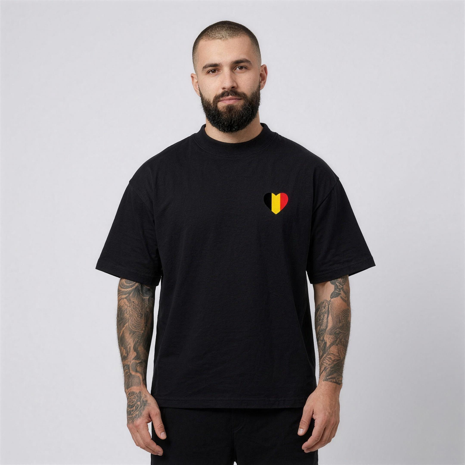 T-shirt belge oversized noir porté par un homme, cœur drapeau belge sur la poitrine gauche