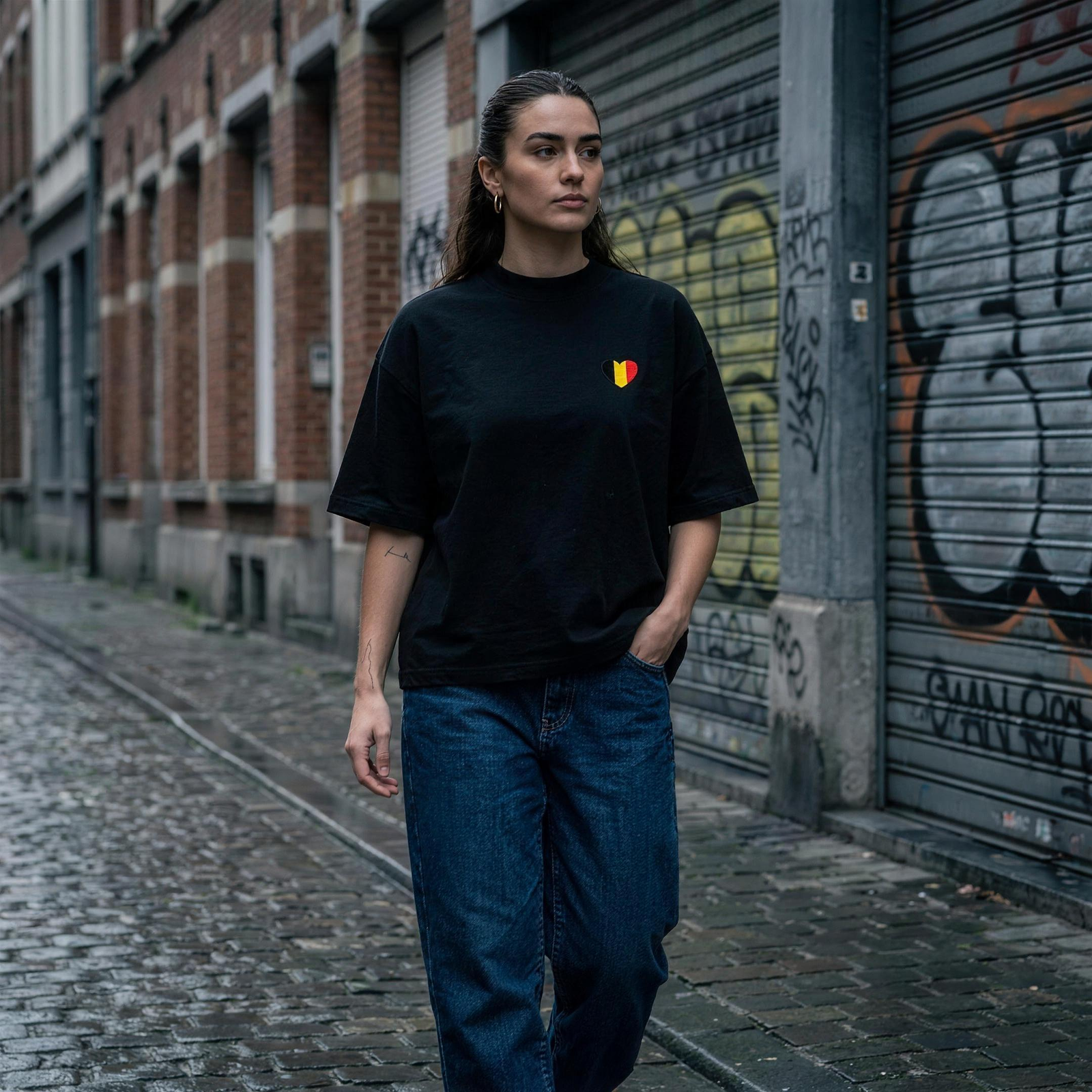Femme en t-shirt belge oversized noir et jean baggy dans une rue de Bruxelles