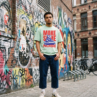 T-shirt oversized vert menthe chat DJ, porté devant un mur de graffitis colorés dans une rue pavée belge