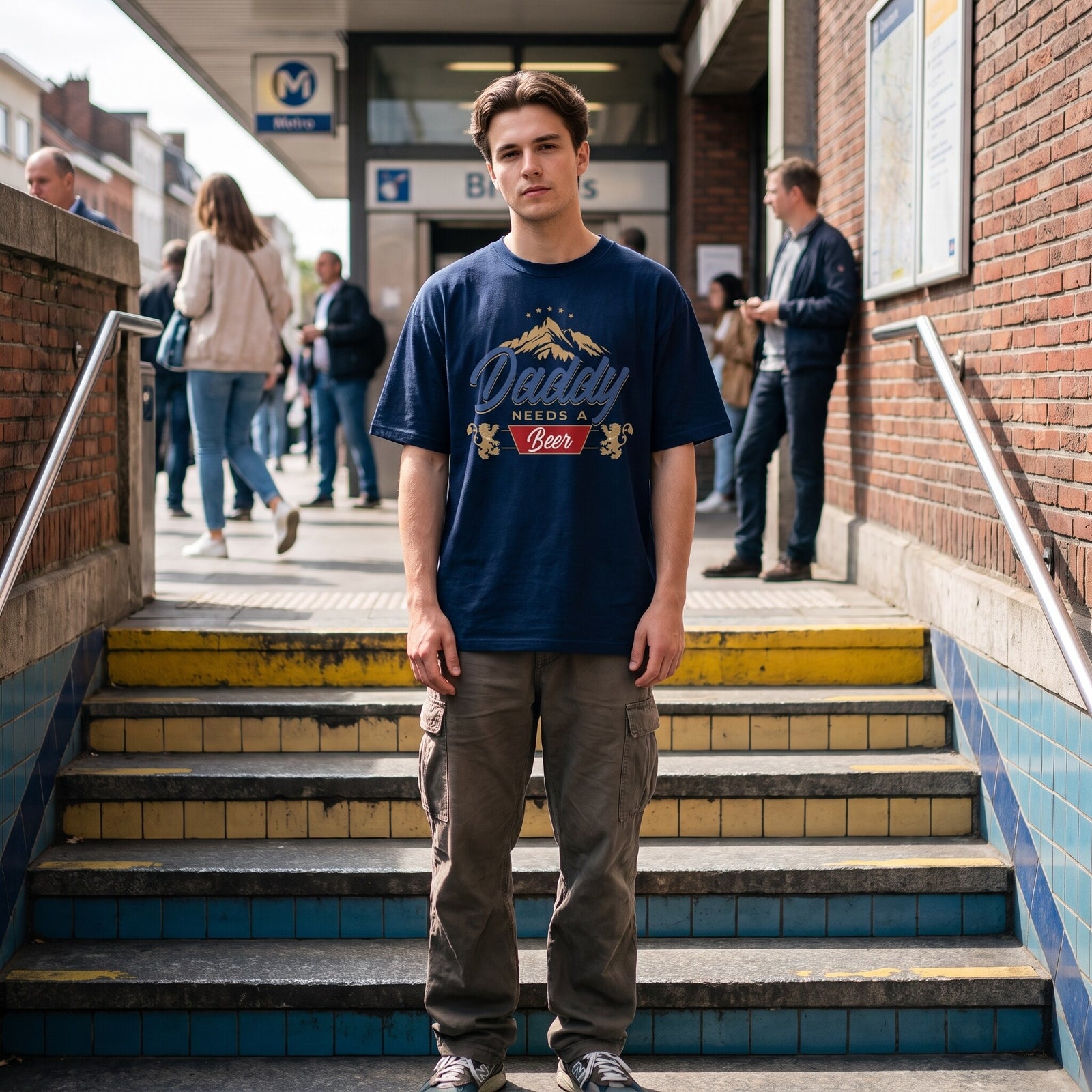 T-shirt oversized bleu marine à blason bière et lions belges, porté avec un cargo beige à l'entrée du métro