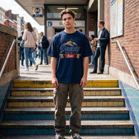 T-shirt oversized bleu marine à blason bière et lions belges, porté avec un cargo beige à l'entrée du métro