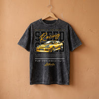 T-shirt enfant delave noir a la voiture JDM jaune, suspendu sur un cintre en bois devant un mur terracotta
