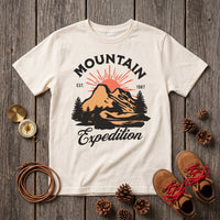 T-shirt enfant ecru Mountain Expedition a plat sur planches grises, boussole, pommes de pin et chaussures de rando