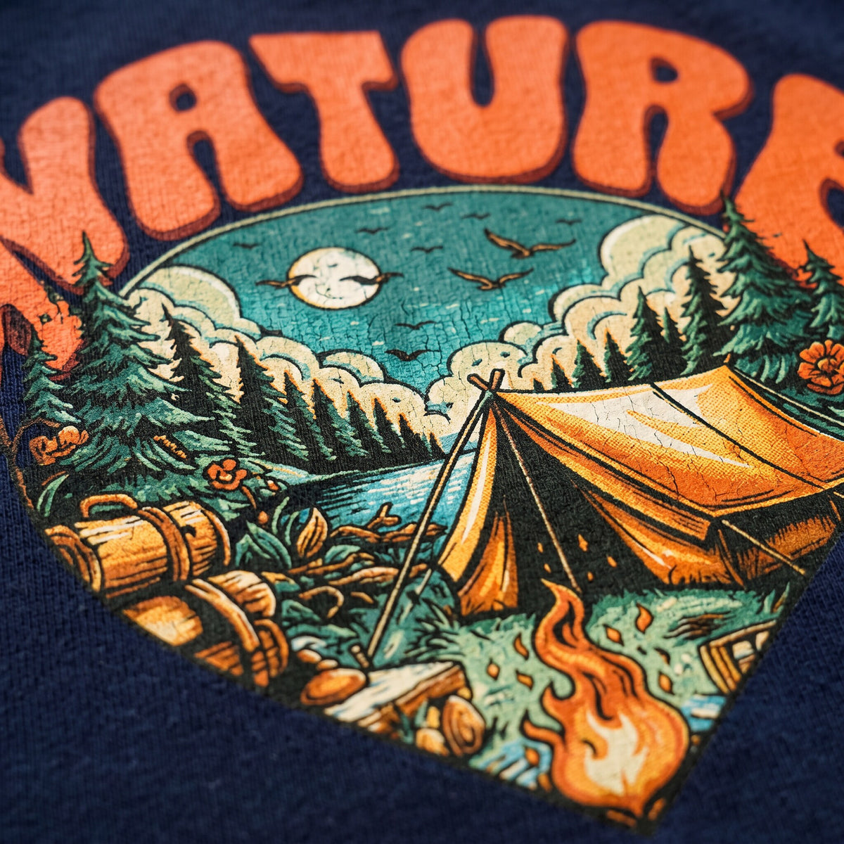 Gros plan sur l'imprime Nature, tente orange, sapins et feu de camp, sur du coton bleu marine texture