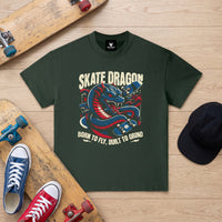 T-shirt enfant vert fonce Skate Dragon a plat sur un parquet clair, entre deux skateboards et des Converse colorees