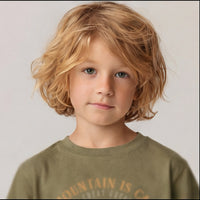 Portrait rapproché d'un enfant en t-shirt kaki, haut de l'imprimé montagne vintage visible