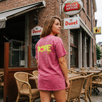 Dos d'un t-shirt oversized rose délavé au lettrage DOPE et crâne fluo, coin de brasserie en brique