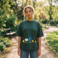 T-shirt oversized vert sapin à petites fleurs cartoon, porté par une femme dans l'allée ensoleillée d'un parc