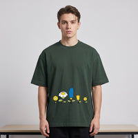 T-shirt oversized vert sapin au rang de fleurs cartoon jaunes et bleue, porté en studio devant un fond blanc