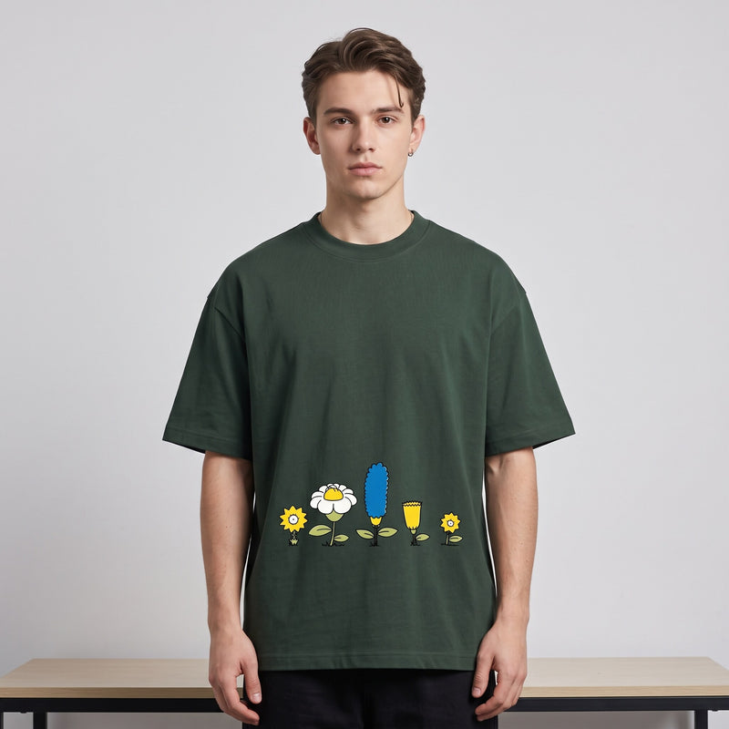 T-shirt oversized vert sapin au rang de fleurs cartoon jaunes et bleue, porté en studio devant un fond blanc
