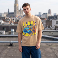 T-shirt sable I Love Beaches et jean large, portes sur un toit gravillonne dominant les toits de la ville