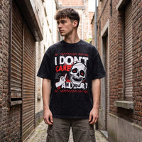 T-shirt noir délavé à imprimé crâne et doigt d'honneur, porté de face dans une ruelle bordée de briques rouges