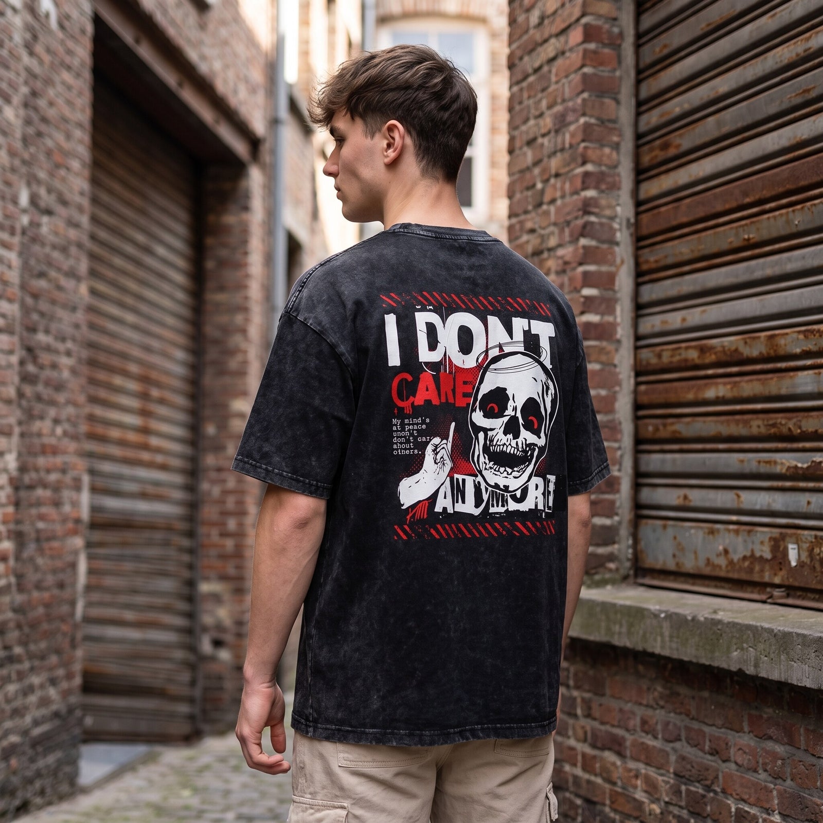Imprimé crâne I Don't Care Anymore au dos d'un t-shirt noir délavé, porté avec un short beige dans une venelle