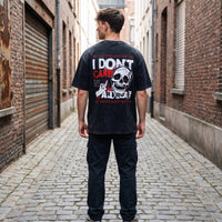 T-shirt oversized noir snow wash vu de dos, imprimé crâne rouge et blanc, debout au milieu d'une ruelle pavée