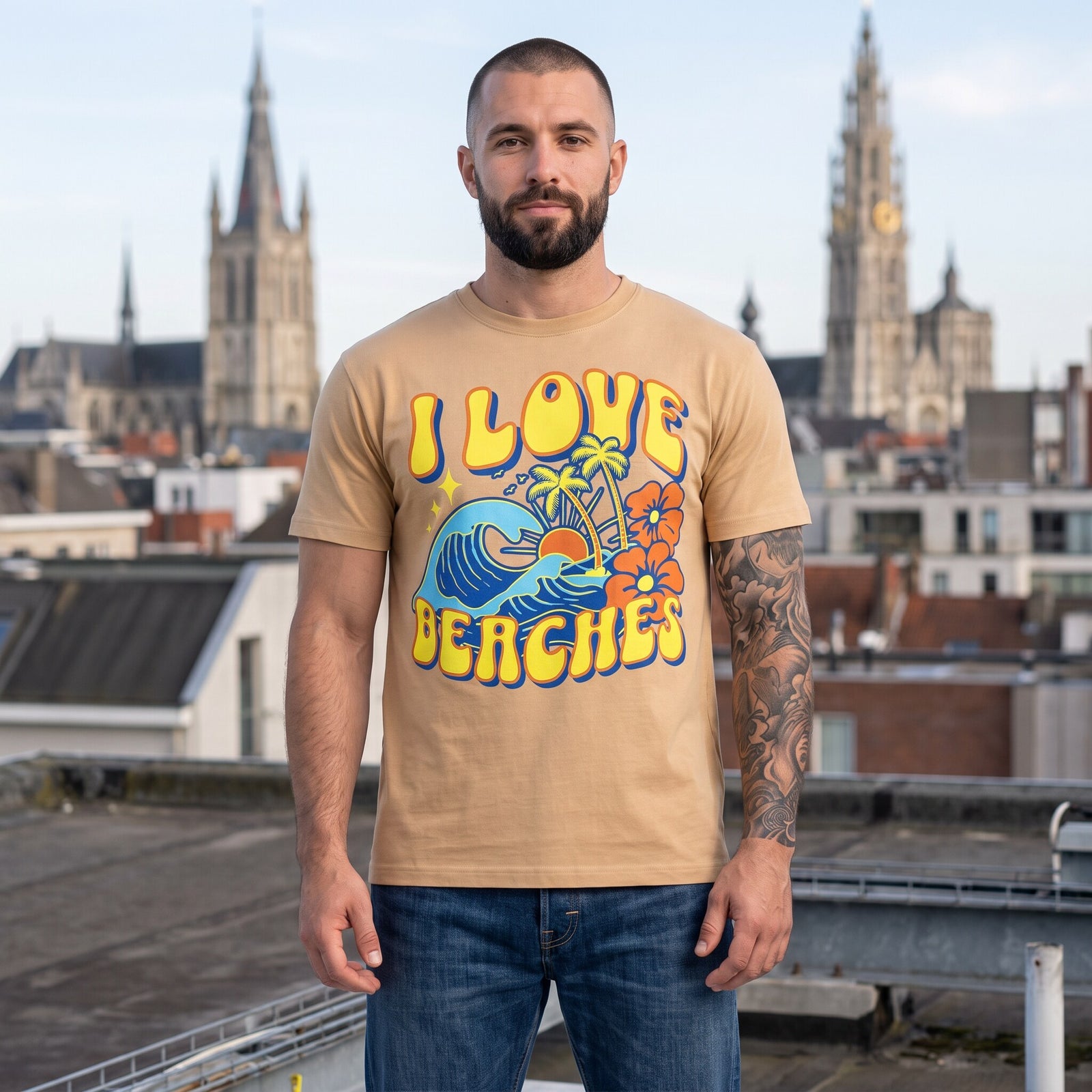 T-shirt beige imprime vague, palmiers et hibiscus, porte par un homme barbu tatoue sur un toit face au beffroi