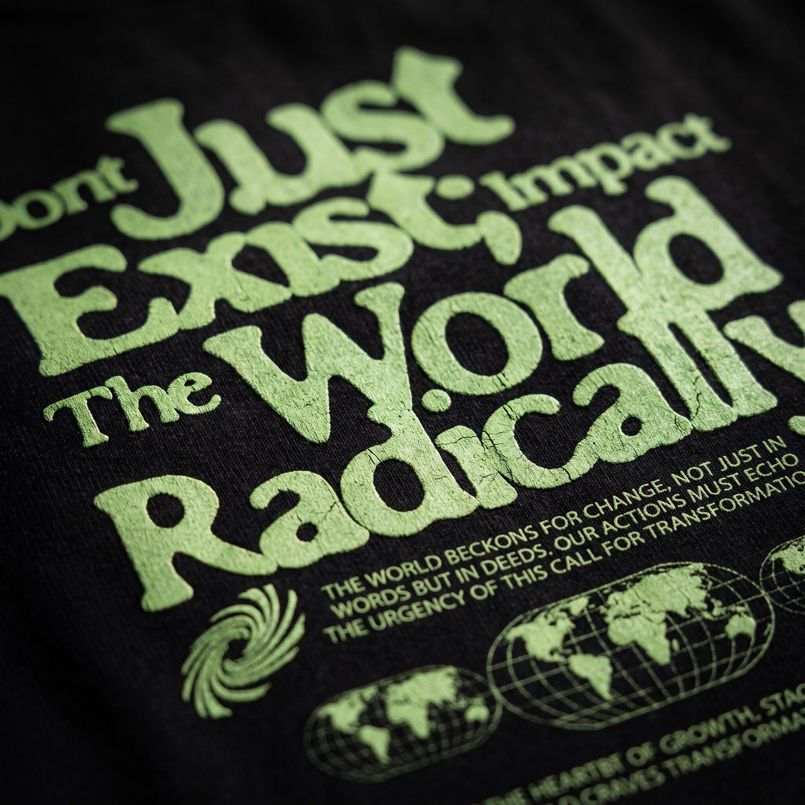 Gros plan sur l'impression vert clair Impact The World Radically et les globes terrestres sur le coton noir