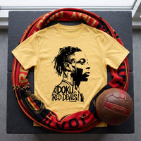 T-shirt jaune Doku Red Devils posé à plat sur une ardoise, entouré d'une écharpe des Diables Rouges et d'un ballon en cuir